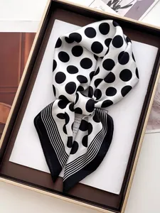 Close-up of elegant black polka dot silk scarf with striped edges and satin texture