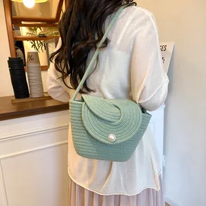 Handmade green woven crossbody bag with pearl button closure and slim shoulder strap