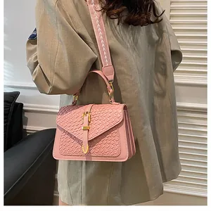Detail of light pink woven leather handbag with gold metal clasp and floral wide strap