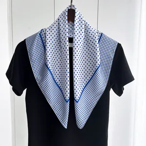 Close-up of elegant blue polka dot silk scarf with dark blue contrast border detail