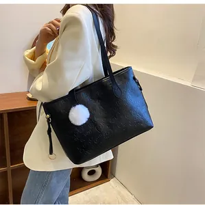 Détail du sac cabas en cuir noir avec motifs embossés et breloque pompon en fourrure blanche