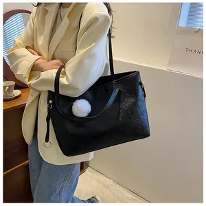 Détail d'un sac cabas noir gaufré avec motifs de dessins animés et pendentif en peluche