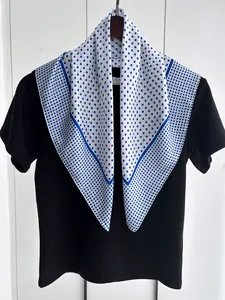 Close-up of silk-like polka dot scarf with blue borders on black mannequin top