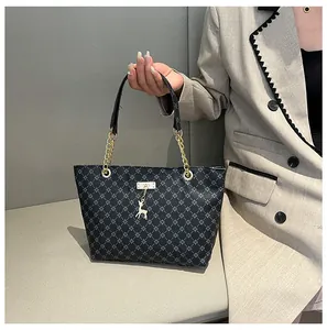 Detalle del bolso tote con monograma, cadena dorada y elegante colgante de ciervo
