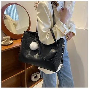 Détail du grand sac cabas noir gaufré avec motif love et pendentif pompon blanc soyeux