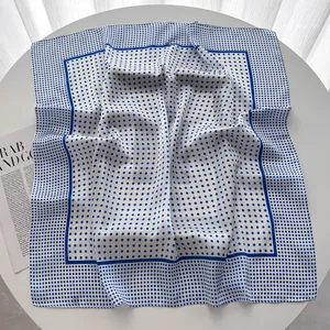Close-up of a blue polka dot silk scarf with dark blue borders on a bright table