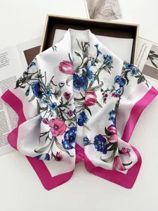 Close-up of floral print silk scarf with pink borders in a minimalist gift box