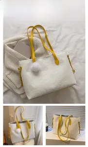 Détail du sac cabas blanc avec motifs embossés, anses jaunes et accessoire boule en peluche