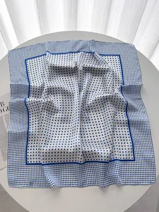 Macro detail of silk-like square scarf featuring blue polka dots and a double-striped border