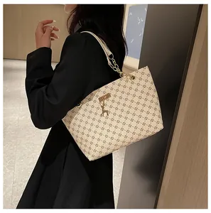Detalle del bolso tote con monograma, cadena dorada y colgante de ciervo decorativo
