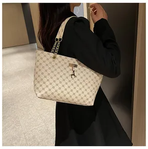 Detalle del bolso tote beige con monograma y colgante de ciervo dorado
