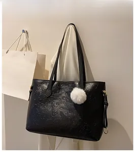 Détail du sac cabas noir gaufré avec motifs de dessins animés et pompon blanc doux