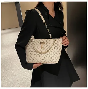 Detalle del bolso tote beige con monograma, patrones de cruz negra y colgante de ciervo