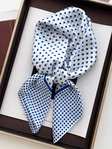 Detailed view of polka dot silk scarf in royal blue and white on a display card