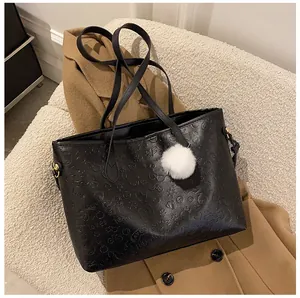 Détail du sac cabas noir à motifs gaufrés avec pendentif pompon blanc en fausse fourrure