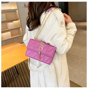 Detail van paarse gewatteerde crossbodytas met gouden kwastje op een witte jas