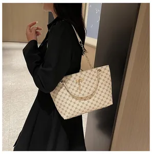 Detalle del bolso tote beige claro con patrones geométricos y colgante de ciervo dorado