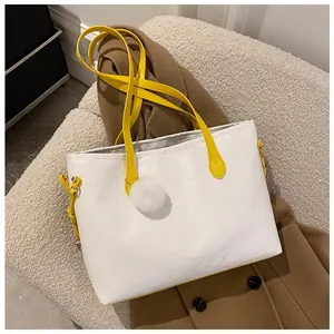 Détail d'un sac cabas blanc gaufré avec anses jaunes et accessoire pompon