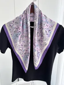 Detail of silk square scarf with floral abstract pattern draped on black shirt