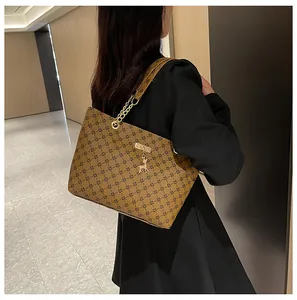 Detalle del bolso tote vintage con monograma, cadena dorada y colgante de ciervo