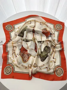 Detail of luxury silk square scarf with chain and equestrian pattern on table