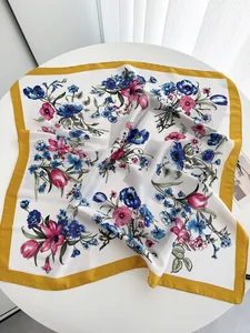Close-up of a floral silk scarf with blue tulips and yellow borders in a soft texture