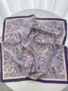 Detail of a square silk scarf with floral patterns on a white table with soft lighting