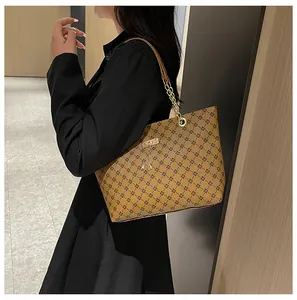 Bolso tote marrón con cadena y colgante de ciervo mostrado sobre el hombro