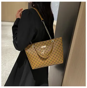 Detalle del bolso tote marrón vintage con patrones geométricos y colgante de ciervo