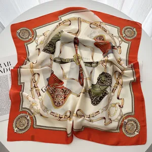 Detail of silk square scarf featuring equestrian chain horse bit patterns in orange and cream