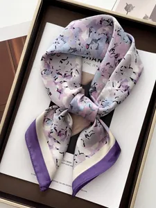 Detailed view of floral silk scarf folded on a magazine with elegant purple borders