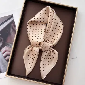 Detail of silk-like beige scarf with black polka dots on a premium display tray