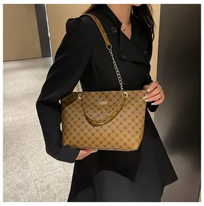 Detalle del bolso tote vintage marrón con monograma y correa de cadena dorada fija