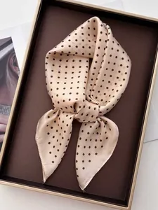 Detailed view of apricot silk-like scarf with brown polka dots on a display tray