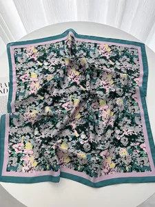 Detailed view of large square silk scarf showing floral patterns and emerald border