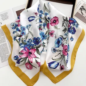 Detail of silk square scarf with vibrant floral patterns and yellow border trim