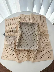 Detailed view of the beige silk-like square scarf featuring classic black polka dot prints