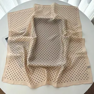 Detailed close-up of premium polka dot silk scarf with elegant hemmed edges and smooth texture