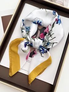 Detail of silk square scarf with floral print and mustard yellow border on a tray