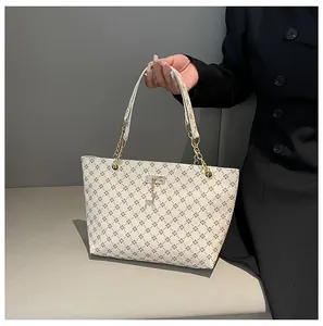 Detalle del bolso crema con estampado floral negro vintage y colgante de ciervo dorado