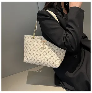 Detalle de bolso tote vintage con estampado de monograma, colgante de ciervo y cadena
