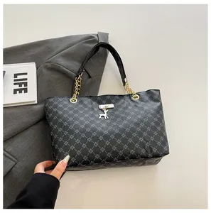 Detalle del bolso tote con monograma gris, colgante de ciervo plateado y asa de cadena