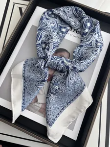 Blue and white paisley silk scarf displayed on a magazine within a black tray