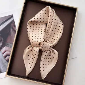 Elegant champagne faux silk scarf with black polka dots styled in a chic bow tie knot