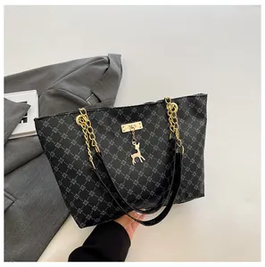 Detalle del bolso tote negro con estampado geométrico y colgante de ciervo dorado