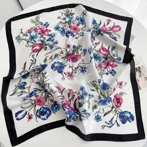 Detailed macro shot of floral print silk scarf with black border on a white table