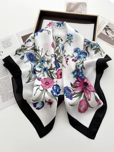 Detailed view of floral silk scarf with colorful flower print in a wooden tray
