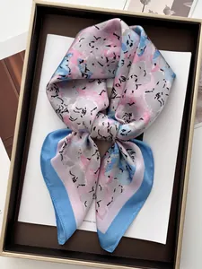 Detail of silk-like floral scarf in pink, blue and grey inside a gold-rimmed gift box