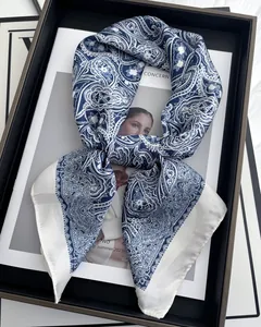Detailed view of blue and white paisley silk scarf folded on a fashion magazine