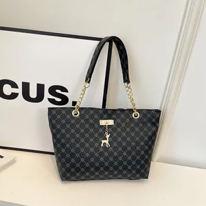 Bolso tote clásico negro con monograma, colgante de ciervo dorado y asas de cadena